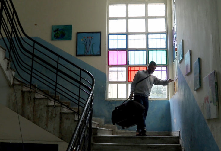 ATHENS, GREECE (EU) 05-29-2017: Hosem Al Rahmoun carries some of his family's belongings to an awaiting taxi. Today his family is moving into their new apartment after living in a refugee squat in an abandoned school building in Athens for the past few months. They are being sponsored by two sisters in New York who raised money for them through HumanWire's Tent-to-Home Project, the new apartment is a welcome relief from the refugee camps they had been living in, one with conditions so dire that the mother, Manar, had resorted to sucking on the ears and faces of her children to keep them clean. They were looking forward to moving into a place of their own, even though it was temporary.