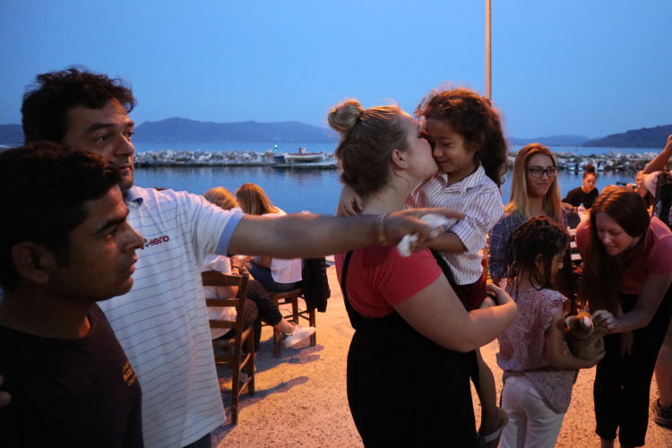 LESVOS, GREECE (EU)  06/03/2017: Refugees and volunteers from the nearby Moria Refugee camp socialize before dinner at "Home for All," the Mytileni restaurant that serves dinner each night to refugees for free on the island of Lesvos. A gathering point for donations of goods and emotional support, Home is run by restaurant owners Nikos and Katerina Katsouris, and has become an important gathering point for donations of goods and emotional support, for refugees.