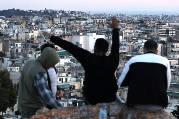 05-30-2017 ATHENS, GREECE (EU): A group of refugees relax on Strefi Hill, a rare rustic green space in the Exarcheia neighborhood of Athens which provides panoramic views stretching over city rooftops to the Acropolis.