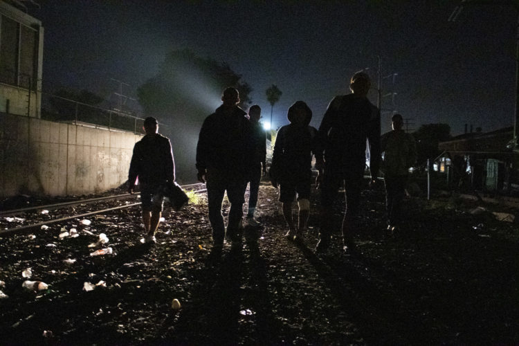 GUADALAJARA, MEXICO  07-13-2017: A group of Honduran migrants walk along the railroad tracks in Guadalajara, roughly the midway between Central American and the U.S. looking for a position to jump onto the trains, known as The Beast. According to the Migration Policy Institute (MPI), a half a million Central American immigrants ride atop La Bestia during their long and perilous journey through Mexico to the U.S. The migrants often must latch onto the moving freights, which run along multiple lines, carry products north for export, and must ride atop the moving trains, facing physical dangers that range from amputation to death if they fall or are pushed. Beyond the dangers of the trains themselves, Central American migrants are subject to extortion and violence at the hands of the gangs and organized-crime groups that control the routes north.