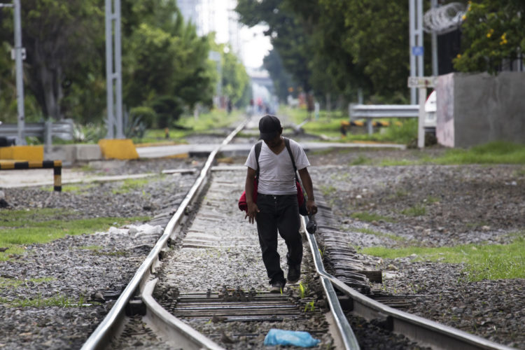 GUADALAJARA, MEXICO  07/14/2017: A migrant walks along the railroad tracks in Guadalajara where the Mexican freight train known as La Bestia (the Beast) that is utilized by U.S. bound migrants on their journey to the United States to more quickly traverse the length of Mexico. This mode of travel is extremely dangerous and illegal. Guadalajara, roughly the midway between Central American and the U.S. border.

According to the Migration Policy Institute (MPI), a half a million Central American immigrants ride atop La Bestia during their long and perilous journey through Mexico to the U.S. The migrants often must latch onto the moving freights, which run along multiple lines, carry products north for export, and must ride atop the moving trains, facing physical dangers that range from amputation to death if they fall or are pushed. Beyond the dangers of the trains themselves, Central American migrants are subject to extortion and violence at the hands of the gangs and organized-crime groups that control the routes north.