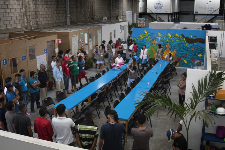 GUADALAJARA, MEXICO   07/13/2017  Migrants gather for a pre-lunch prayer inside the dining area of the FM4 Paso Libre in Guadalajara. The migrant shelter provides a clean and safe place for migrants to rest, wash and eat, while volunteers from non-governmental organizations offer clean clothes, medical attention, and free legal and psychological counseling. 

M4 Paso Libre was started by a group of students in 2007 and opened its first kitchen and day shelter in 2010. The nonprofit is a member of the Office of the United Nations High Commissioner for Refugees (UNHCR), assists approximately 8,000 migrants each year, and relies on regular donations and hundreds of volunteers to support the migrants who pass through.