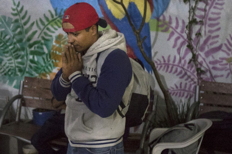 GUADALAJARA, MEXICO  07-13-2017: A Honduran migrant makes a silent prayer before departing the FM4 Paso Libre migrant shelter in Guadalajara, continuing on the hazardous journey from Central America to the U.S. border aboard the freight train known as The Beast. Here they have a chance to rest, wash and eat, while volunteers from non-governmental organizations offer a place to sleep, clean clothes, medical attention, and legal and psychological counseling.