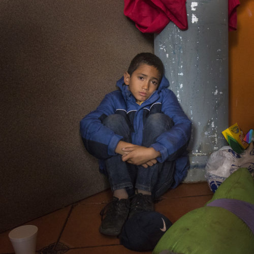 TIJUANA, MEXICO  03-09-2019: Patric Murillo, 12, of Honduras, sits on the floor of a cafe in Tijuana that offers free food to migrants. He just arrived with his mother and two brothers after traveling for two months in a migrant caravan from Honduras. The Border Angels volunteers then brought them clean clothes, hygiene products and directions to the nearby shelter.
