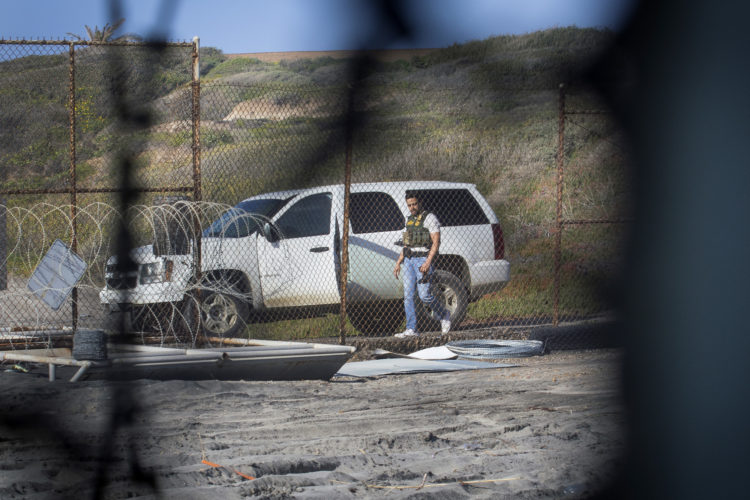 TIJUANA, MX   03/13/2019: A CBP agent gets into an SUV on the U.S. side of the border fence, after a group of migrants pushed through an opening in the border fence on the beach running past a CBP agent and ran north along the beach into the United States.
