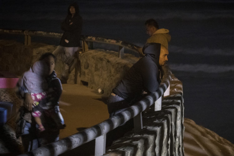 TIJUANA, MEXICO  03-13-2019: Light from the CBP on the U.S. side of the border wall casts shadows on the Mexico side at La Playa in Tijuana, where earlier that day a group of migrants squeezed through an opening in the border fence there and ran past a CBP agents along the beach into the United States. They were later captured by United CBP agents, who said they arrested about 52 migrants, including 23 men, between the ages of 18 to 53, 12 women aged 21 to 50, and 17 minors between the ages of 1 and 14 years old. They were mostly from Honduras and came to Tijuana in a caravan. As they broke through the fence and ran down the beach, some dropped clothes and shoes from the backpacks, as some people on the Mexico side cheered them on.