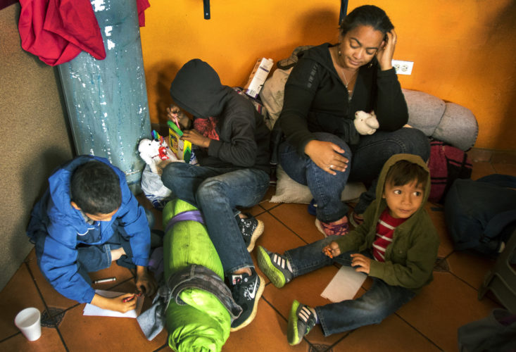 TIJUANA, MEXICO  03-09-2019: Isabela Murillo, with her sons Patric, 12, Jose, 14, and Mateo, 3, of Honduras, sit on the floor of a cafe in Tijuana that offers free food to migrants. Along with her other son Patric, not pictured, they just arrived at the border after traveling for two months in a migrant caravan from Central America. The Border Angels volunteers brought them clean clothes, shoes, and hygiene products then helped them get to the nearby shelter, where they would spend the night before trying to apply for asylum in the U.S.
