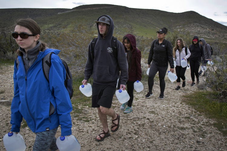 IMPERIAL COUNTY, CA 03/10/2019:  Border Angels led a team of volunteers, including a group of students from University of Utah, and carried gallons of water into the Imperial Valley in southeastern Southern California near the Mexico border and hid the plastic bottles scattered along trails that undocumented migrants often take after crossing into the California.  Along the trails, discarded items such as makeshift foot coverings migrants use to avoid leaving footprints could be seen as well as other discarded clothes and remnants of campfires. The conditions here are extreme, often were windy and cold at night, and extremely ward during the daytime.
Border Angels is a nonprofit that has been leading humanitarian efforts such as “water drops” in the desert for migrants for over 20-years. In 2019, two border aid volunteers were sentenced to 15 months of probation, must pay fines for dropping off water and food intended for migrants crossing through a protected desert area in southern Arizona.