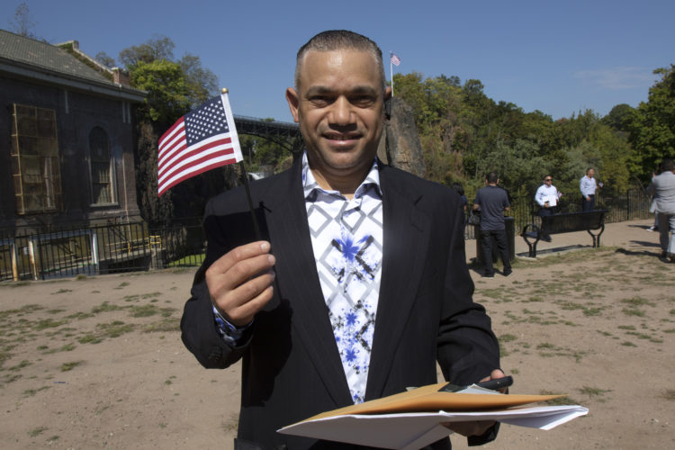 PATERSON, NJ  10-02-2019 NATURALIZATION CEREMONY AT GREAT FALLS:  Elvin Molina DeLeon waves the U.S, flag after taking the Oath of Allegiance to the United States. He is from the Dominican Republic. The Paterson Great Falls National Historical Park (NPS), in partnership with U.S. Citizenship and Immigration Services (USCIS), held a naturalization ceremony in the park’s new amphitheater where 40 new citizens, mostly residents of Paterson, took the Oath of Allegiance to the United States.
