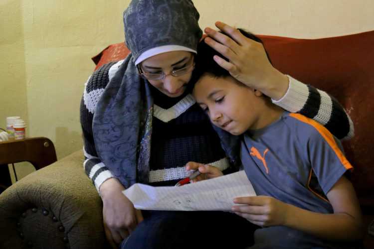 ELIZABETH, NJ   04/03/2016   SYRIAN REFUGEE FAMILIES RESETTLED IN ELIZABETH: Samer Zakkour hugs her son Mohammad, 9, as he shows her a drawing he made, in the family's apartment in Elizabeth where the IRC resettled them. The Zakkour's fled their home in Homs, Syria, after it became unsafe due to aerial bombings, They fled to Jordan where they were remained for 4-years before being resettled in Elizabeth by the IRC.