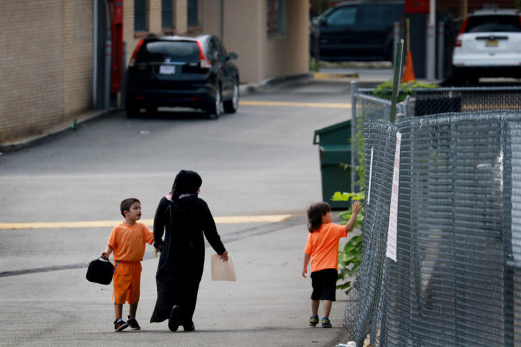 ELIZABETH, NJ  07-26-2016 SUMMER CAMP FOR SYRIAN CHILDREN:  Maryam Al Radi holds hands with her two boys at the end of the day after leaving the Elizabeth YMCA. 16 Syrian children recently relocated to New Jersey with their families from their war torn homeland,  attended a fun-filled summer camp thanks to the generosity of two North Jersey Jewish synagogues,  Bnai Keshet in Montclair and Temple Bnai Abraham in Livingston,  and the Elizabeth YMCA. At the camp the 16 refugee children had the opportunity to play outdoor and indoor games, interact with other children, and improve their English. The children ages 5-14, were able to take respite from the summer heat, after the groups teamed up to raise the necessary funds for the two-week recreation and educational program.