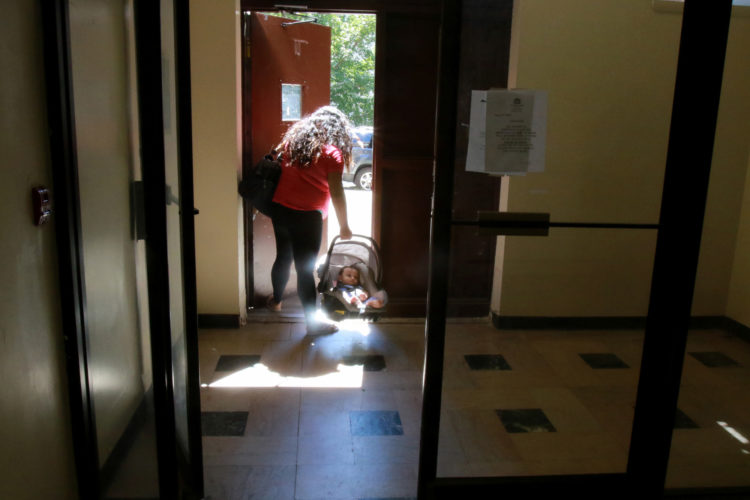 NEWARK, NJ  07-19-2018: Kasandra Serrano, 21, carries her 9-month old son Ismael as they leave the apartment complex where she is living with her mother and sisters. Serrano's fiancé Daniel Castro, 28, was taken into custody by Newark Police in June 2018 and turned over to ICE despite Newark's Sanctuary City policy. Castro, who is undocumented but has no criminal record and did not commit any offense the evening of his arrest, was falsely arrested, and Newark Police admit they made a mistake in violating the city's own Sanctuary City policy. On the night of his arrest, Castro was returning from shopping for baby formula when he was stopped by police and reluctantly gave his name when they arrested him for an outstanding ICE warrant from many years ago for which he said he was never notified. After many months of being held at the Elizabeth Detention Center (ICE) he was deported to his native Nicaragua where he currently awaiting a status hearing in New Jersey. The couple has a 9-month old baby boy, Ismael, and since Danny's arrest Serrano has been living with her mother, sisters, and their young children in a small apartment in Newark, and says she cannot support herself and the baby without government and family assistance.