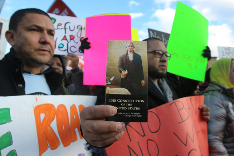 ELIZABETH, NJ  01-29-2016: Rally participant Carlos Castaneda holds a pamphlet of the U.S. Constitution at an immigration-rights rally outside the Elizabeth immigration detention facility (ICE), where roughly 2,000 protesters marched calling for an end to President Donald Trump's executive order on immigration. The executive order stops the processing of Syrian refugees, suspends the broader refugee program, calls for a more intense vetting system, and imposes a three-month ban on immigration from Iraq, Syria, Iran, Sudan, Libya, Somalia and Yemen.The measure was later blocked by a federal judge.