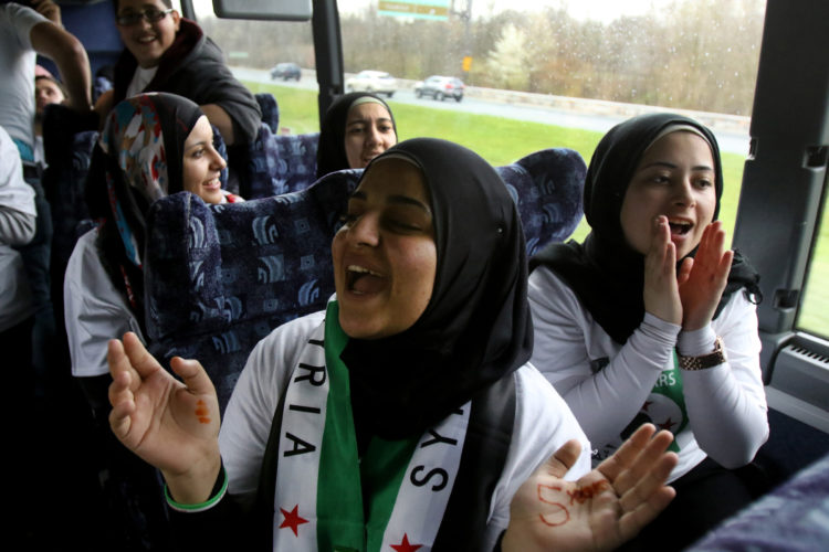 PATERSON, NJ   03/20/2016: Syrian refugee Noha Aizouabi,17, claps and sings with her friends as they ride aboard a chartered bus from Paterson, NJ, to Washington DC, to take part in the “March for Syrian Freedom” rally, marking the 5-year anniversary of the Syrian uprising. Aizouabi's family fled the civil war in Syria and came to the US in 2012. At right is Rasha Alrifae, age 18 also from Paterson. The rally, which commemorates the 5th anniversary of when the conflict began as an anti-government uprising with protesters taking to the streets on March 15, 2011, was designed to bring attention to the global humanitarian crisis and raise money to aid Syrian refugees worldwide. The program will include an interfaith conference at the Lincoln memorial, to be followed by a march to the White House.