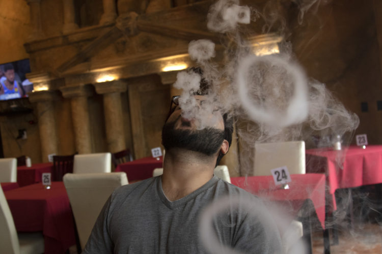 04-14-19 PATERSON, NJ:  Danny Usmani, 26, blows smoke rings as he enjoys a hookah at Darna in South Paterson. Darna serves Lebanese and Mediterranean food in a large space that can seat around 300, and features  a waterfalls and a terra-cotta replica of that famed architectural site in Jordan, Petra, seen on the wall behind them. He is from Teaneck, NJ.